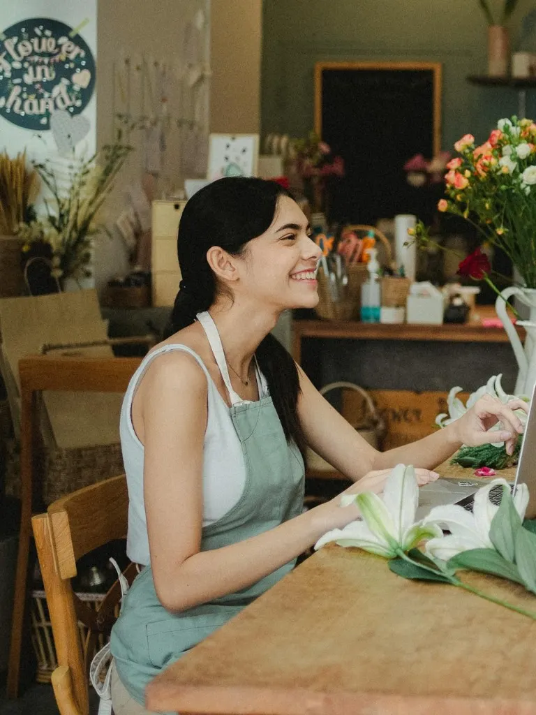 Florista sonriente en su florería con laptop