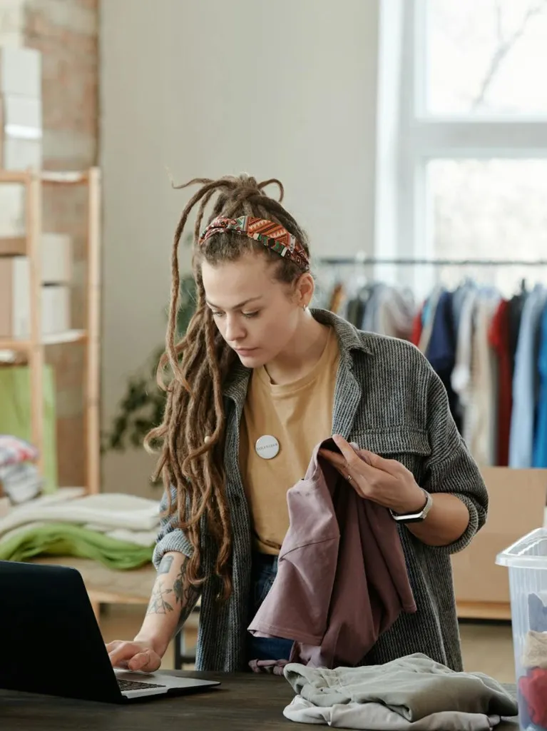 Emprendedora gestionando inventario de ropa con laptop